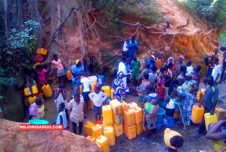 plusieurs personnes qui s'alignent en rang pour s'approvisionner à l'eau de la source à Gobongo